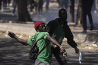 A demonstrators throws rocks at riot policemen during protests against the arrest of opposition leader and former presidential candidate Ousmane Sonko, Senegal, Monday, March 8, 2021. Senegalese authorities have freed opposition leader Ousmane Sonko while he awaits trial on charges of rape and making death threats. The case already has sparked deadly protests threatening to erode Senegal's reputation as one of West Africa’s most stable democracies. That's because Sonko's supporters are accusing President Macky Sall of pursuing the criminal charges to derail the opposition figure's prospects in the upcoming 2024 election. (AP Photo/Leo Correa)