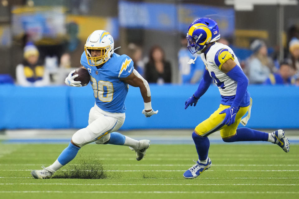 Los Angeles Chargers running back Austin Ekeler (30) runs the ball under defense by Los Angeles Rams cornerback Cobie Durant (14) during the second half of an NFL football game Sunday, Jan. 1, 2023, in Inglewood, Calif. (AP Photo/Marcio Jose Sanchez)