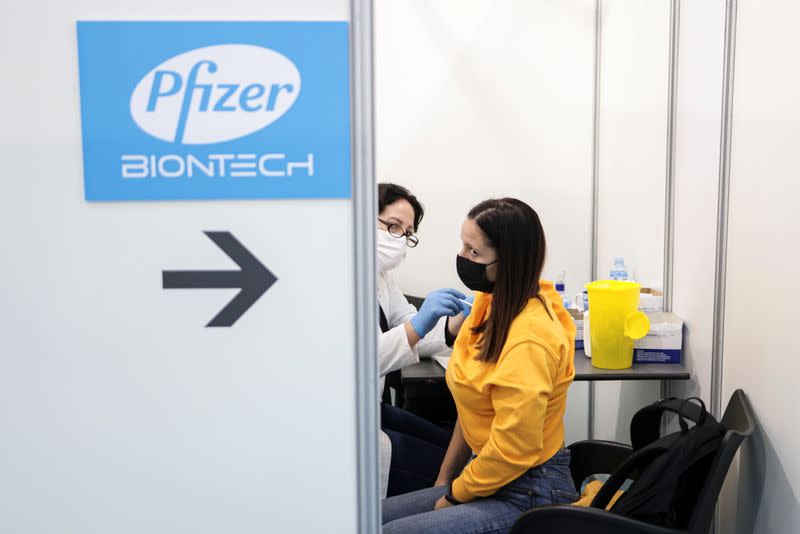 A healthcare worker administers a dose of Pfizer's coronavirus disease (COVID-19) vaccine to a woman at Belgrade Fair vaccination center in Belgrade