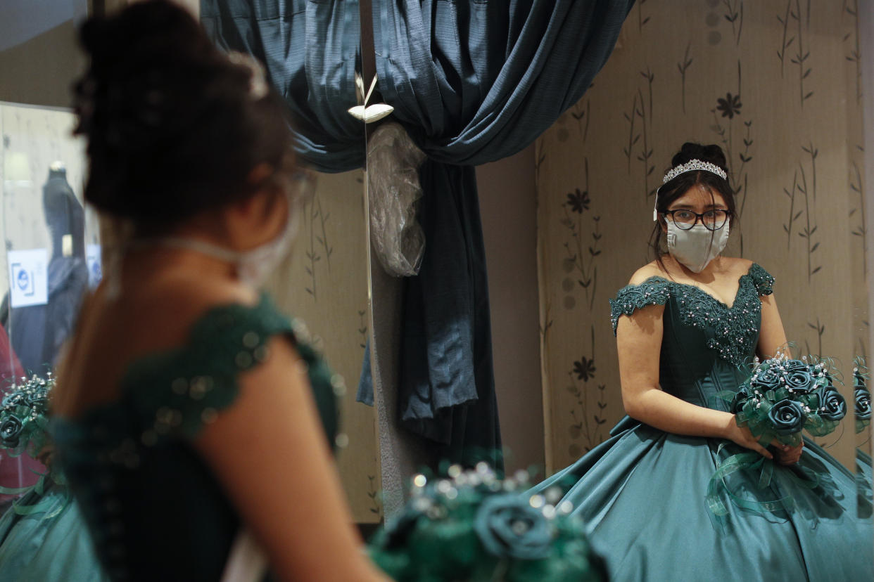 Ximena Canejo Hernández mira su reflejo en un espejo mientras se prueba su vestido de quinceañera elegido, en el centro de la ciudad de México. Foto: Rebecca Blackwell / AP