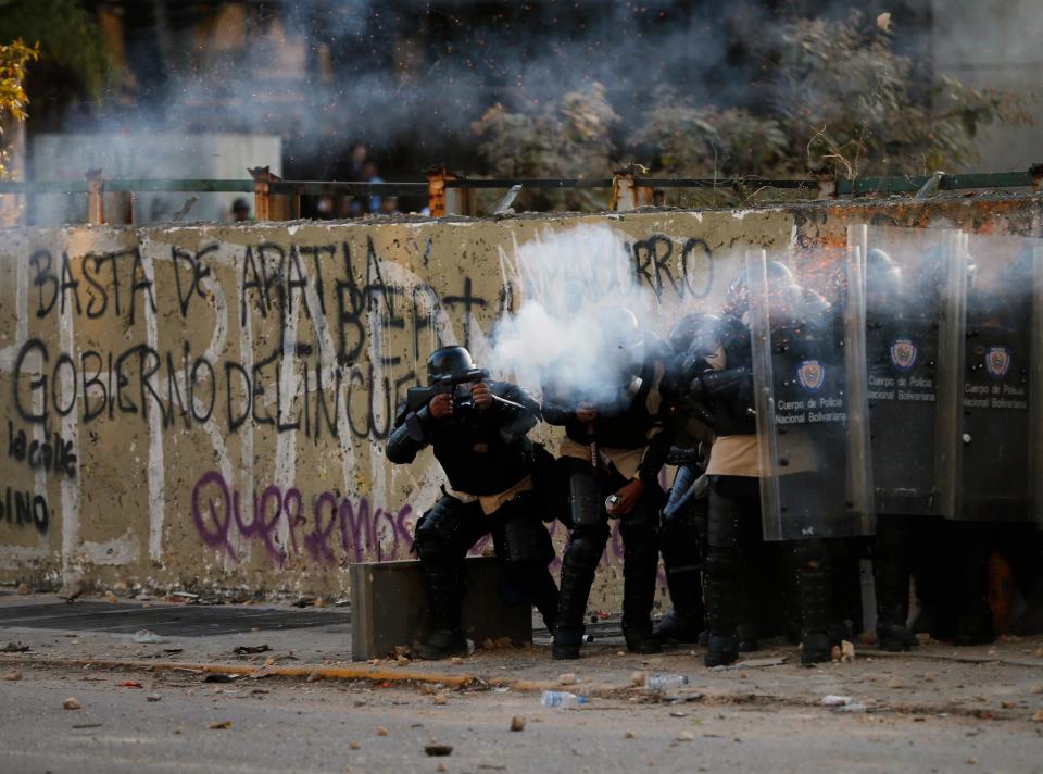 Bolivarian national police officers fire teargas at demonstrators during clashes in Caracas, Venezuela, Wednesday, March 5, 2014. The one year anniversary of the death of Venezuela's former President Hugo Chavez was marked with a mix of street protests and solemn commemorations that reflected deep divisions over the Venezuela he left behind. (AP Photo/Fernando Llano)