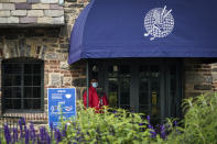 A door attendant wears a protective mask outside the clubhouse on the second day of practices before the U.S. Open Championship golf tournament at Winged Foot Golf Club, Tuesday, Sept. 15, 2020, in Mamaroneck, N.Y. (AP Photo/John Minchillo)