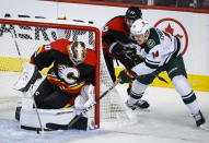 Minnesota Wild forward Joel Eriksson Ek, right, is checked by Calgary Flames defenseman Noah Hanifin, center, as he tries to get the puck past goalie Dan Vladar during the first period of an NHL hockey game Wednesday, Dec. 7, 2022, in Calgary, Alberta. (Jeff McIntosh/The Canadian Press via AP)