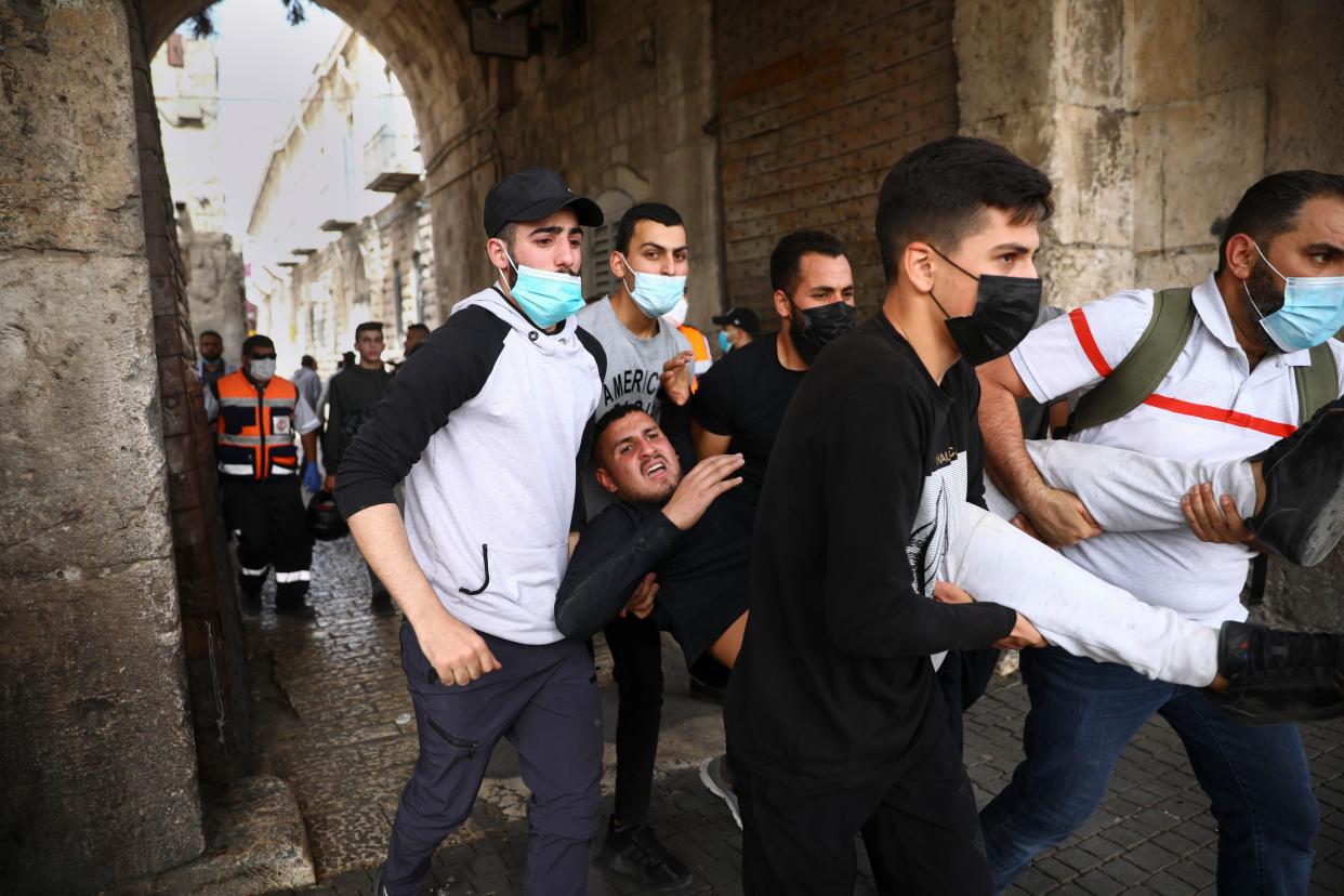 Palestinians evacuate a wounded protester during clashes with Israeli security forces at the Lions Gate in Jerusalem's Old City, Monday, May 10, 2021.