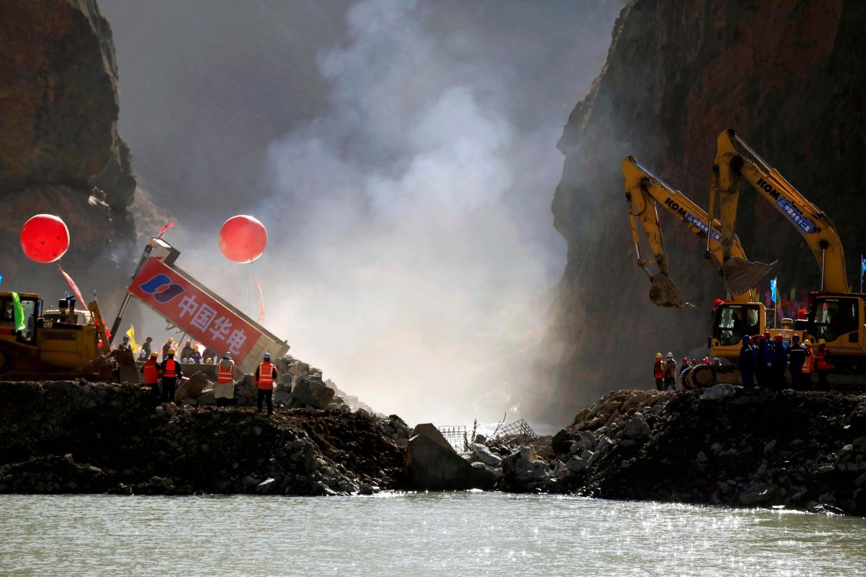 Trucks dump rocks to compete the river closure during the construction of Lawa Hydropower Station at the upper reaches of the Jinsha River on November 29, 2021 in Garze Tibetan Autonomous Prefecture, Sichuan Province of China.