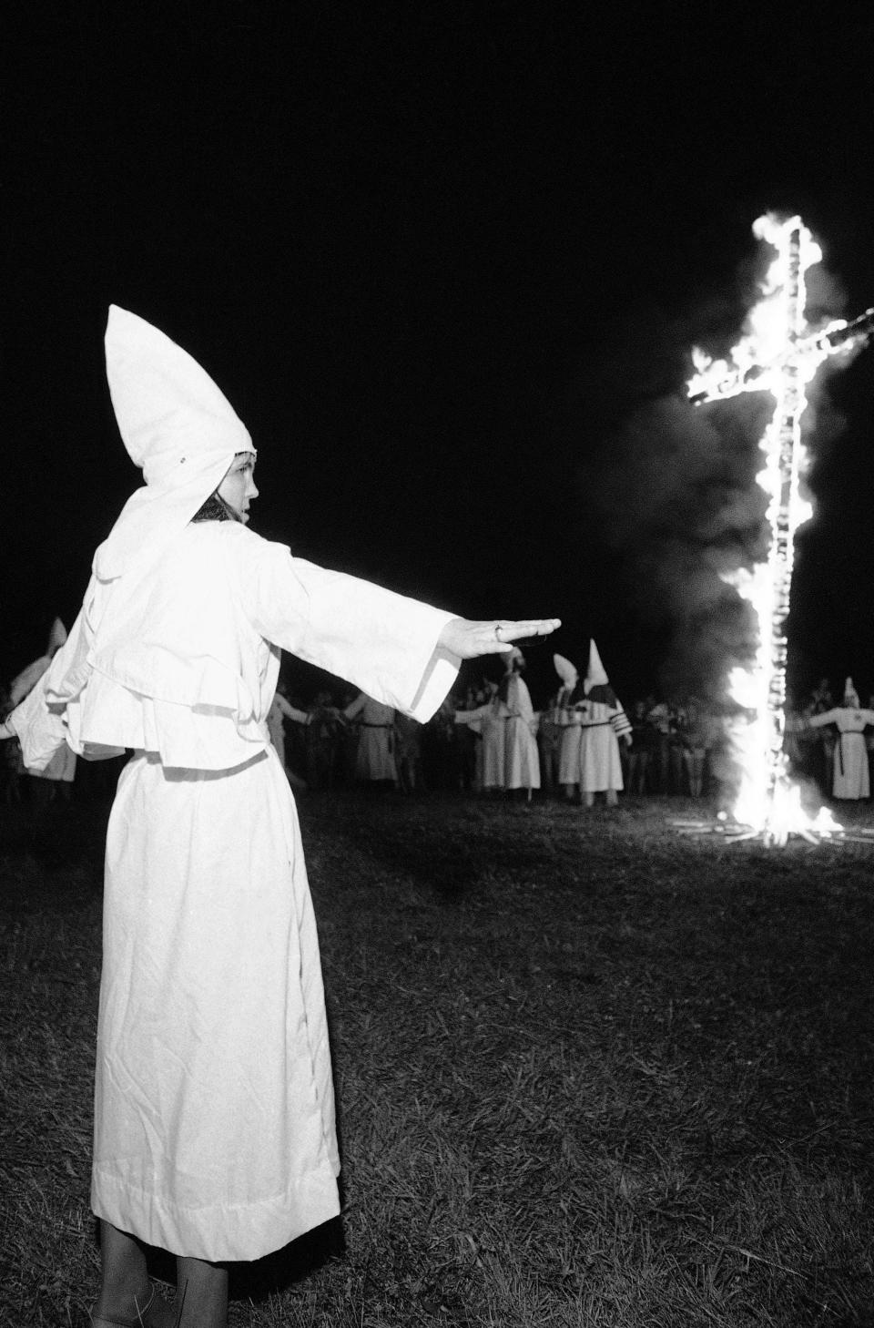 A woman wearing the robe of the Ku Klux Klan spreads her arms during a cross lighting in Middletown, Ohio, on July 23, 1979. One anti-Klan protester was arrested after a confrontation.