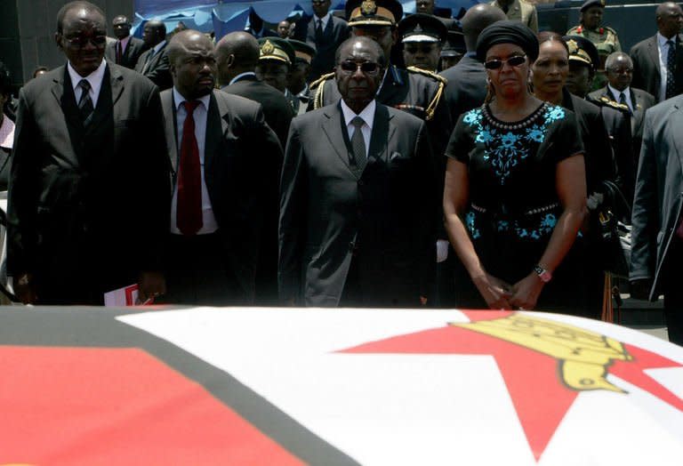 Zimbabwe President Robert Mugabe (centre) looks at the flag-drapped coffin of John Landa Nkomo during funeral ceremony at the National Heroes Acre in Harare, on January 21, 2013