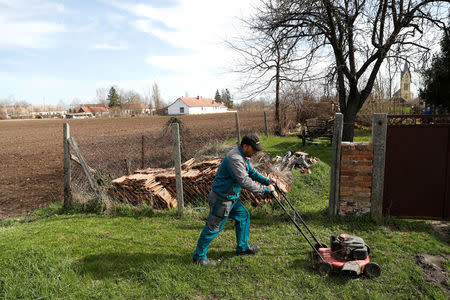 Istvan Barna, 36, cuts grass in the village of Bacsszentgyorgy, Hungary, April 3, 2018. REUTERS/Bernadett Szabo