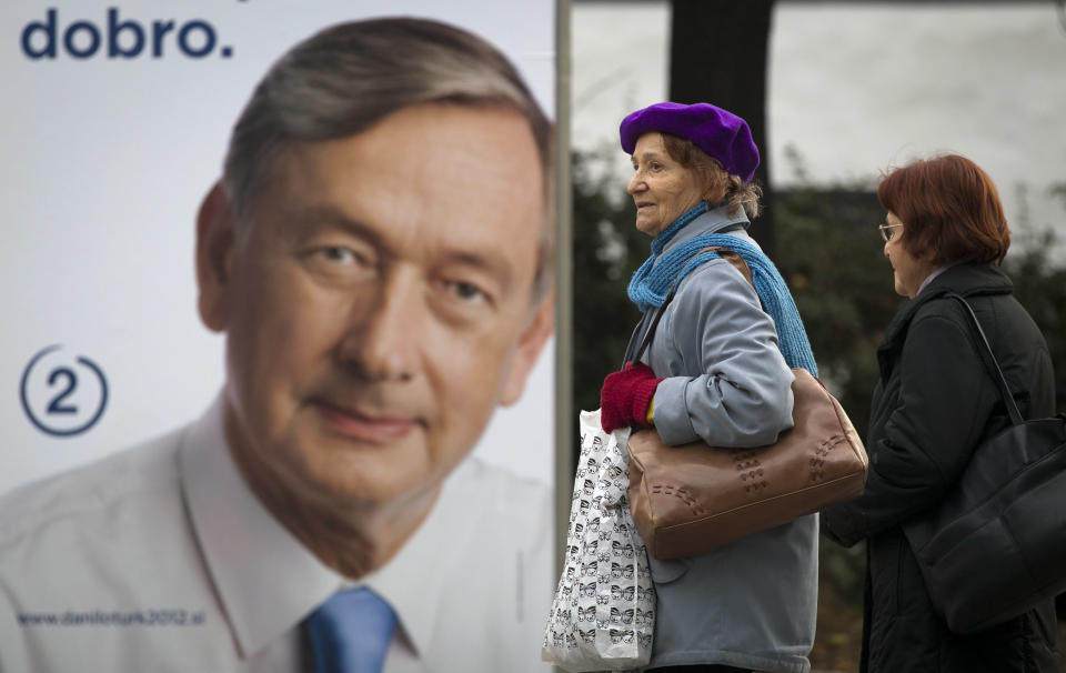 Residents walk past an electoral poster of Danilo Turk in Ljubljana, Slovenia, Saturday, Nov. 10, 2012. Three candidates are vying for the presidency this weekend in crisis-stricken Euro zone member, Slovenia, where deep political divisions have threatened efforts at reforms needed to avoid possible bailout. Incumbent president Danilo Turk is leading the polls. (AP Photo/Darko Bandic)