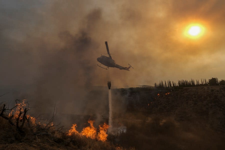 FILE – A helicopter drops water on the Fairview Fire burning on a hillside Thursday, Sept. 8, 2022, near Hemet, Calif. Scientists say a warming planet will lead to hotter, longer and more wildfire-plagued heat waves. (AP Photo/Ringo H.W. Chiu, File)