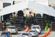 Vehicles line up as a healthcare workers help people check in as they are being tested at the COVID-19 drive-thru testing center at Hard Rock Stadium in Miami Gardens, Fla. on Wednesday, Oct. 28, 2020. (David Santiago/Miami Herald via AP)