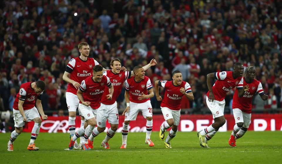 Arsenal's players celebrate as teammate Santi Cazorla (unseen) scores the winning goal of a penalty shoot-out during their English FA Cup semi-final soccer match against Wigan Athletic at Wembley Stadium in London April 12, 2014. REUTERS/Eddie Keogh (BRITAIN - Tags: SPORT SOCCER TPX IMAGES OF THE DAY)