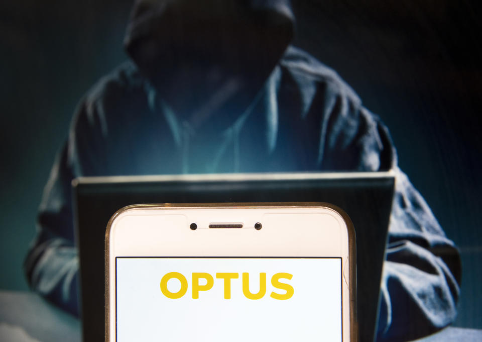 Stylised image of a phone displaying 'Optus' with a shady character engaging in identity theft in the background