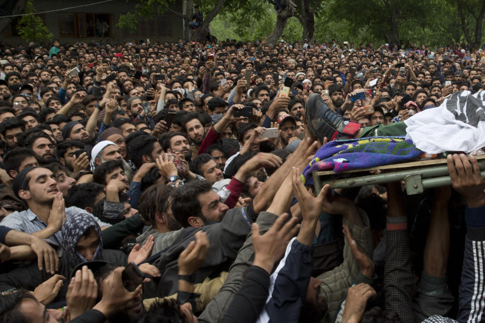 Kashmiri villagers try to touch the feet of top rebel commander Naseer Pandith, during his funeral procession in Pulwama, south of Srinagar, Indian controlled Kashmir, Thursday, May 16, 2019. Three rebels, an army soldier and a civilian were killed early Thursday during a gunbattle in disputed Kashmir that triggered anti-India protests and clashes, officials and residents said.(AP Photo/ Dar Yasin)