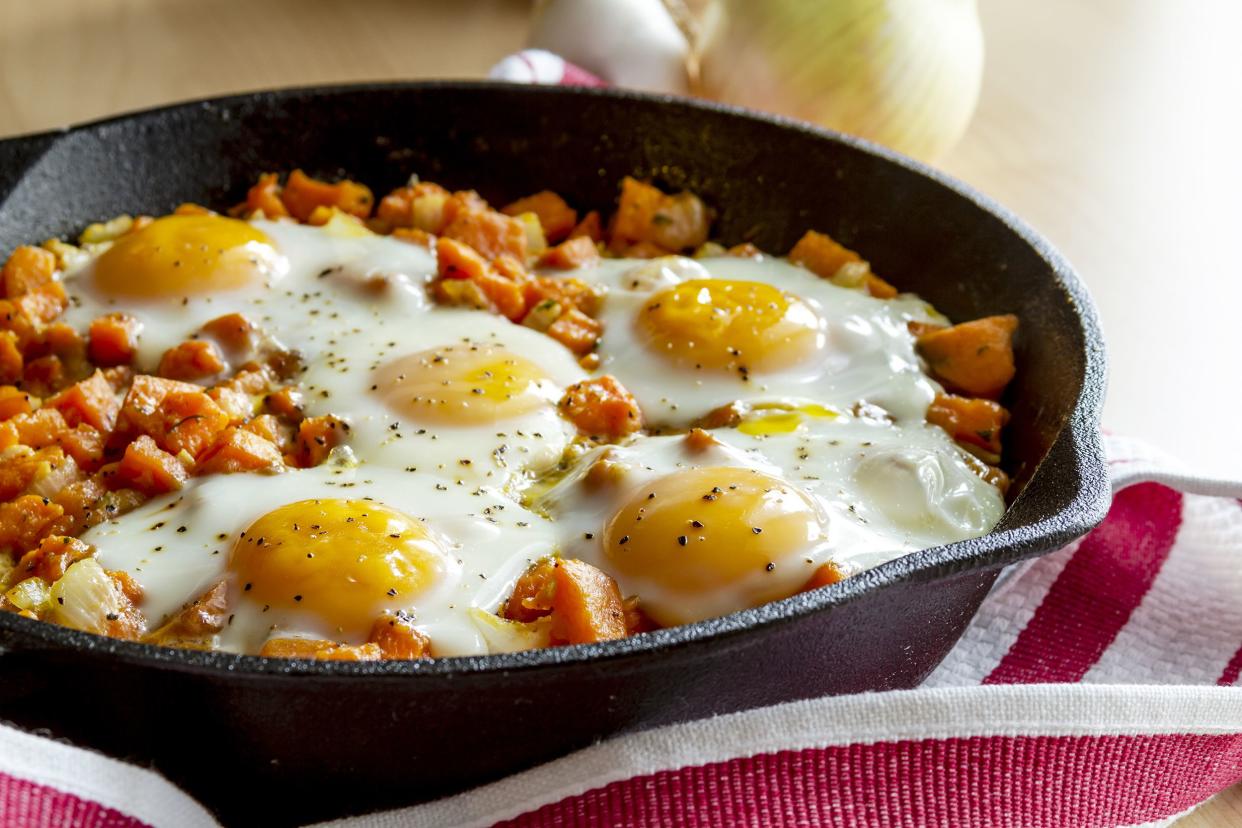 The best potato hash in a cast iron skillet on a napkin on a table with onions