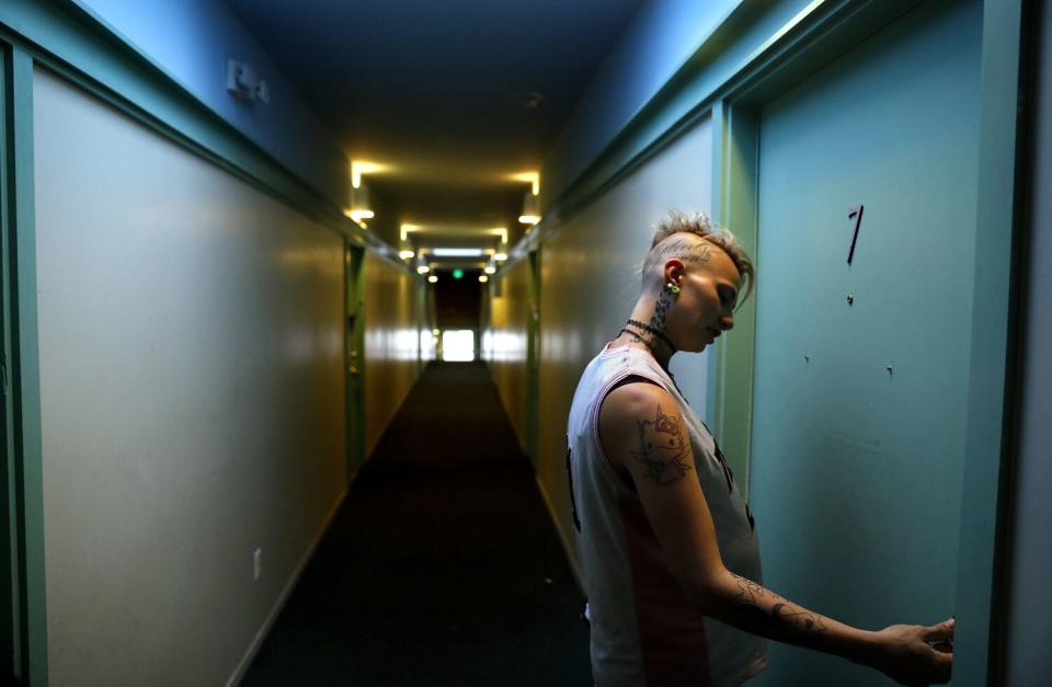 A pregnant woman standing in a hallway about to open a door.