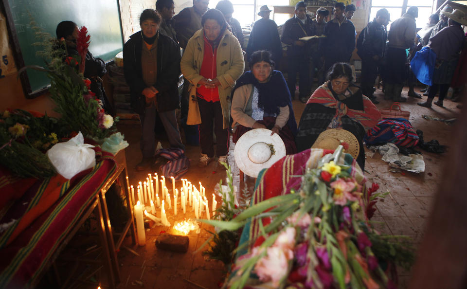 People attend the wake for the persons killed by a mudslide in Chullpa Kasa, Bolivia, Monday, Feb.10, 2014. Heavy rains caused the mudslide that buried much of the small mountainside settlement in central Bolivia, killing at least four people, local officials said Sunday. Eleven more people were listed as missing on Monday. Heavy rains have been falling across most of Bolivia since November and civil defense officials say tens of thousands of families have been affected. (AP Photo/Juan Karita)