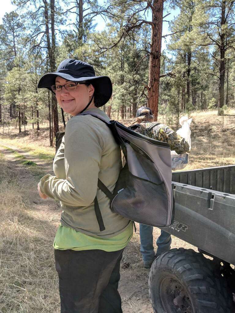 In this 2018 photo provided by the Endangered Wolf Center in Eureka, Mo., center employee Regina Mossotti she walks into the Arizona wilderness with Mexican wolf pups in her backpack, who were born in captivity at the center, to be relocated with foster wolf dens in the wild. Recently, under the supervision of Mossotti, six pups at the center were placed with dens in the wild in an effort to increase population and add genetic diversity. The Mexican wolf, which once numbered in the hundreds of thousands, was nearly extinct before repopulation efforts began in the 1970s. About 150 now live in the wild in the Southwest. (Rachel Crosby/Endangered Wolf Center via AP)