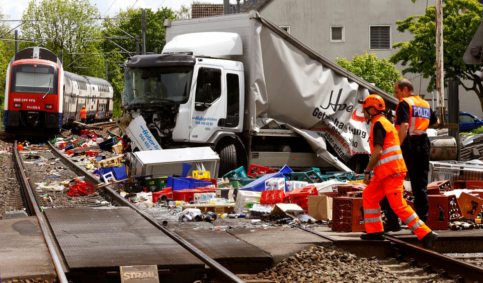 <p>A rescue worker and a Swiss police officer stand beside a truck transporting beverages which crashed with a suburban train on a railroad crossing in Horgen, Switzerland on May 12, 2017. (Photo: Arnd Wiegmann/Reuters) </p>