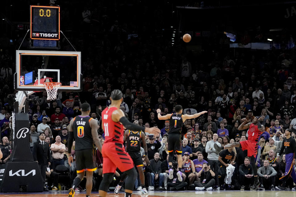 Portland Trail Blazers forward Jerami Grant (9) makes a game-wining shot over Phoenix Suns guard Devin Booker (1) during the second half of an NBA basketball game, Friday, Nov. 4, 2022, in Phoenix. The Trail Blazers defeated the Suns 108-106. (AP Photo/Matt York)