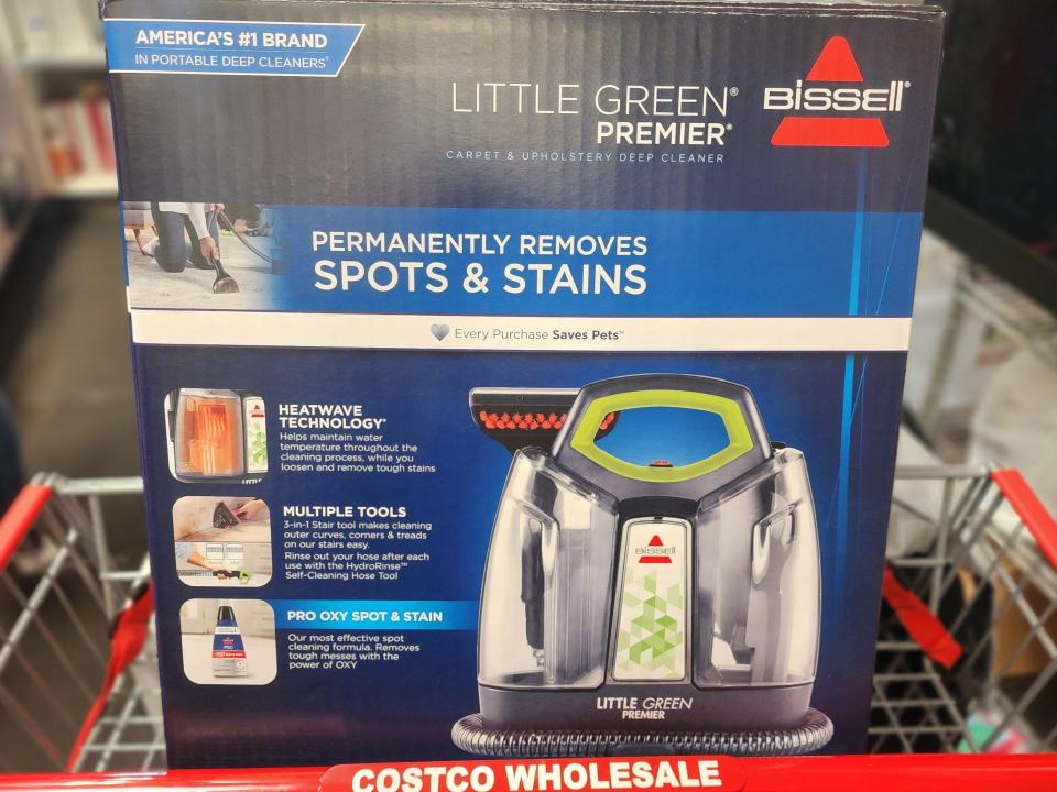 A blue and black box containing the Bissell Little Green premier carpet and upholstery deep cleaner in a Costco shopping cart