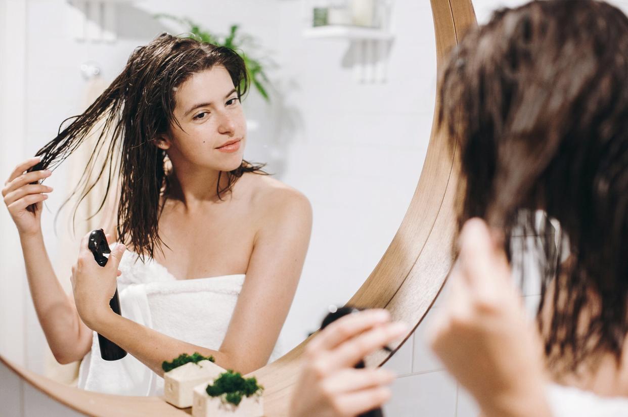 Woman spraying hair with leave-in conditioner mask