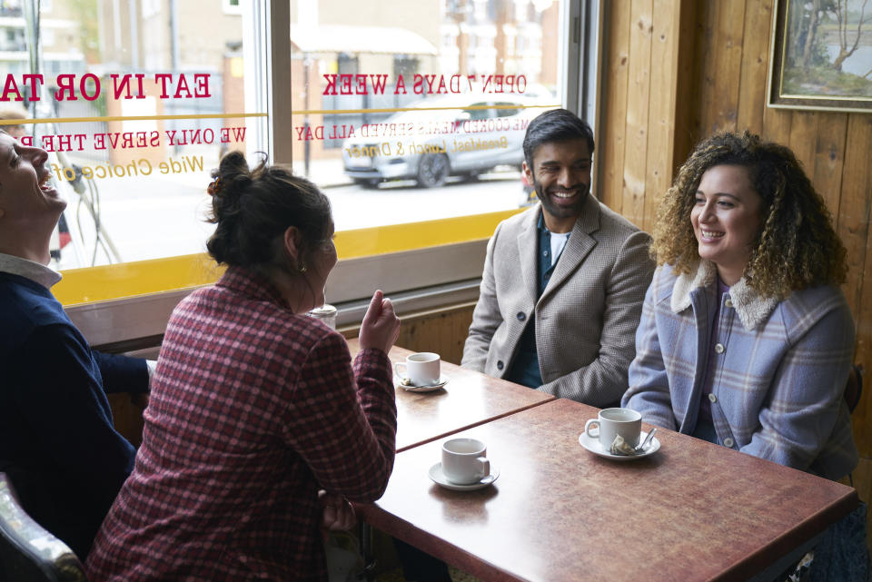 four people sit in a diner and laugh