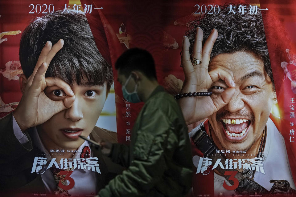 A man wearing a face mask to help curb the spread of the coronavirus walks by a movie poster at Poly Cinema in Beijing on Thursday, Feb. 25, 2021. With coronavirus well under control in China and cinemas running at half capacity, moviegoers are smashing China's box office records, setting a new high mark for ticket sales in February, with domestic productions far outpacing their Hollywood competitors. (AP Photo/Andy Wong)