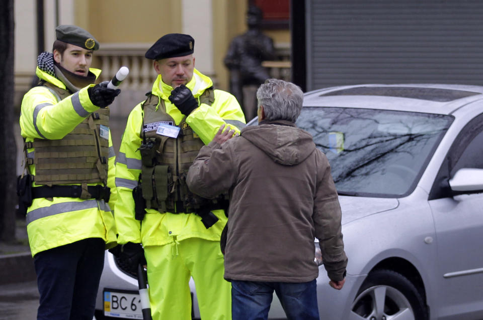 In this photo taken Saturday, Feb. 22, 2014, a man speaks with unarmed "voluntary citizen patrols" wearing bright yellow vests on the street in Lviv, western Ukraine. If Ukraine looks neatly delineated on maps, its often-bloody history is a tangle of invasions and occupations, peoples and religions. It is a place that has been struggling for centuries to define itself. And now it finds itself so sharply divided _ between allegiance to Russia on one side of the country and loyalty to the West on the other _ that it often seems more like two countries than one. (AP Photo/Darko Vojinovic)