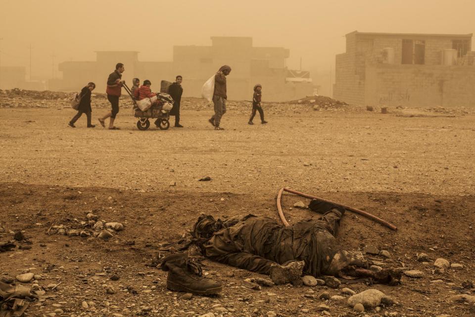 In this Dec. 2, 2016 file photo, a group of civilians pass close to the body of an Islamic State militant, while fleeing from Mosul due to ISIS heavy shelling in several areas under control of the Iraqi Army, Mosul, Iraq, . Most of the fighting in Mosul has been taking place in the city's eastern sector, where Iraq's special forces are making slow progress because of fears over the safety of civilians still inside the city and spirited IS resistance. (AP Photo/Manu Brabo, File)