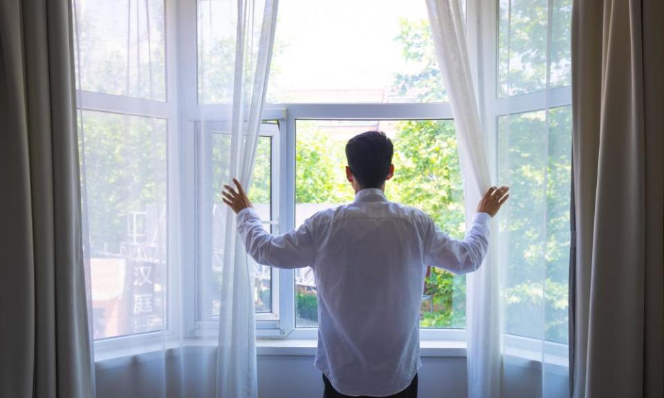 Man opening the curtain in the morning