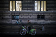 A woman rides a bike as she passes by the Louvre museum during curfew in Paris, Saturday, Oct. 17, 2020. French restaurants, cinemas and theaters are trying to figure out how to survive a new curfew aimed at stemming the flow of record new coronavirus infections. The monthlong curfew came into effect Friday at midnight, and France is deploying 12,000 extra police to enforce it. (AP Photo/Lewis Joly)