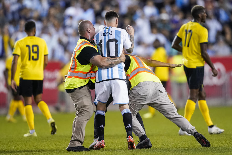 A fan is tackled as he tries to take a selfie with Argentina's player Lionel Messi as he celebrates his goal during the second half of an international friendly soccer match against Jamaica on Tuesday, Sept. 27, 2022, in Harrison, N.J. (AP Photo/Eduardo Munoz Alvarez)