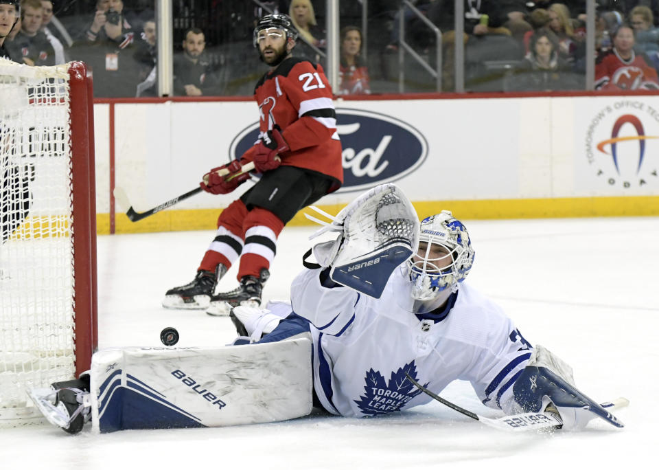 Toronto Maple Leafs goaltender Michael Hutchinson (30) cannot stop the puck as it goes into the net for a goal by New Jersey Devils left wing Jesper Bratt (not shown) as Devils right wing Kyle Palmieri (21) looks on during the second period of an NHL hockey game Friday, Dec. 27, 2019, in Newark, N.J. (AP Photo/Bill Kostroun)
