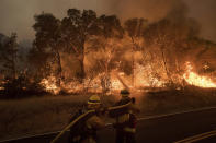 <p>Firefighters battle a wildfire as it threatens to jump a road near Oroville, Calif., on Saturday, July 8, 2017. Evening winds drove the fire through several neighborhoods leveling homes in its path. (AP Photo/Noah Berger) </p>