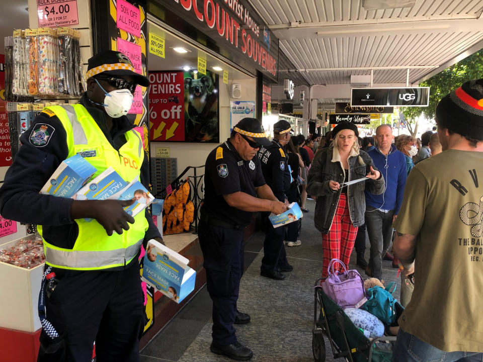Queensland state police community liaison officers hand out face masks to people gathering for the Black Lives Matter protest in Brisbane on Saturday, June 6, 2020. Black Lives Matter protests across Australia proceeded mostly peacefully Saturday as thousands of demonstrators in state capitals honored the memory of Floyd and protested the deaths of indigenous Australians in custody. (AP Photo/John Pye)