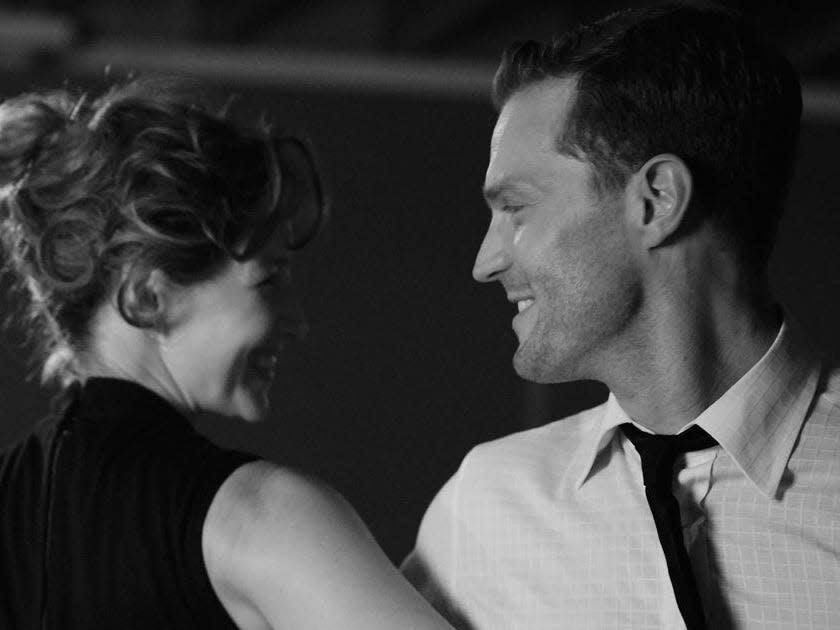 Caitríona Balfe in a black dress and Jamie Dornan in a shirt and tie dancing