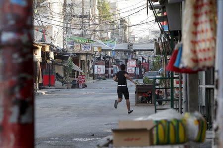 A Palestinian resident runs for cover on an entrance to Ain al-Hilweh Palestinian refugee camp, due to clashes in the area, near the port-city of Sidon, southern Lebanon, August 22, 2015. REUTERS/Ali Hashisho