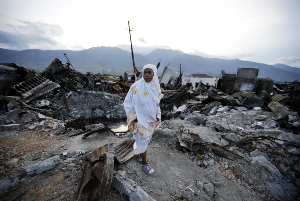 A villager walks by remains of toppled houses at the earthquake damaged neighborhood of Balaroa in Palu, Central Sulawesi, Indonesia Sunday, Oct. 7, 2018. Christians dressed in their tidiest clothes flocked to Sunday sermons in the earthquake and tsunami damaged Indonesian city of Palu, seeking answers as the death toll from the twin disasters breached 1,700 and officials said they feared more than 5,000 others could be missing. (AP Photo/Aaron Favila)