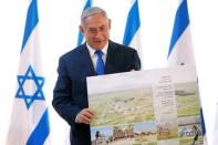 Israeli Prime Minister Benjamin Netanyahu holds up a placard given to him as a gift from Israeli residents of the area, at the start of a weekly cabinet meeting in the Jordan Valley, in the Israeli-occupied West Bank