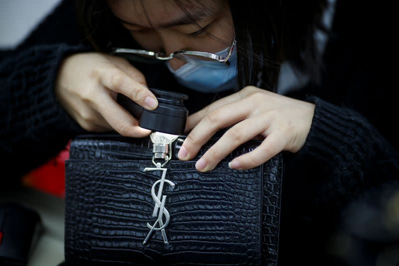 Staff member checks a handbag at the quality control department of the second-hand luxury goods retail platform Plum in Beijing