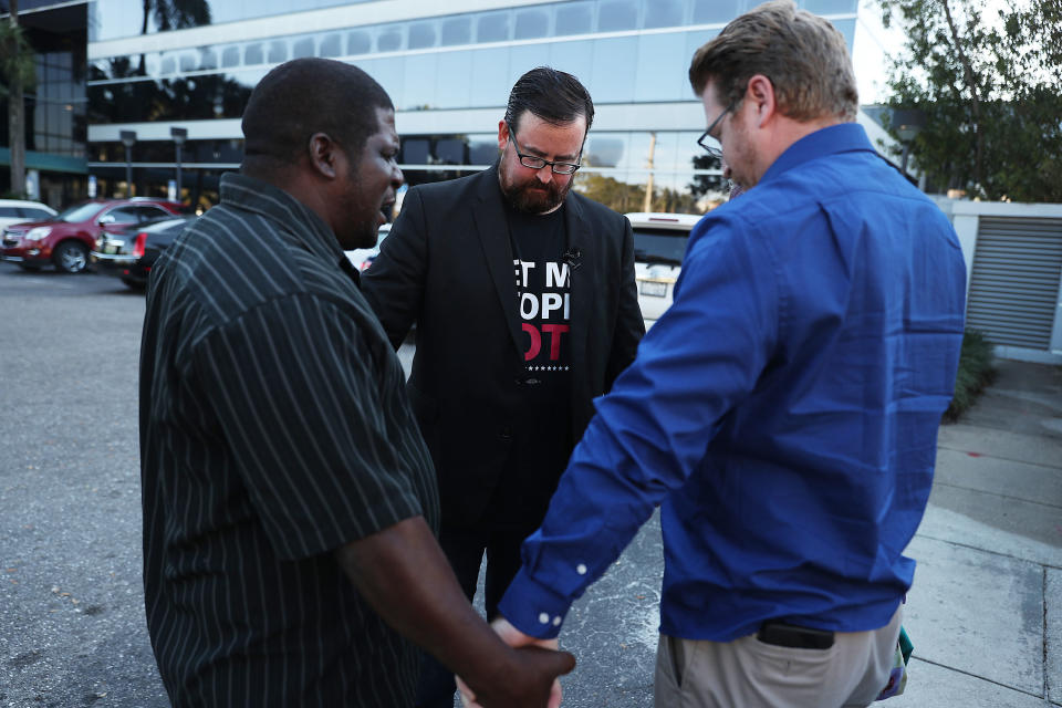 Permon Thomas, Neil Volz and Lance Wissinger clasp hands, as Thomas delivers a prayer.