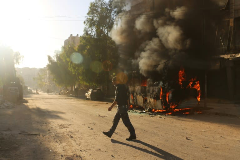 A Syrian man walks past a bus set ablaze following a reported air strike in the rebel-held Salaheddin district of Aleppo