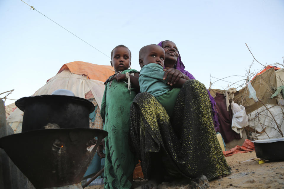 An internal displaced woman with her children cooks food near their makeshift shelter in Daynile camp in Mogadishu, Somalia on Thursday Dec. 17, 2020. As richer countries race to distribute COVID-19 vaccines, Somalia remains the rare place where much of the population hasn't taken the coronavirus seriously. Some fear that’s proven to be deadlier than anyone knows. (AP Photo/Farah Abdi Warsameh)