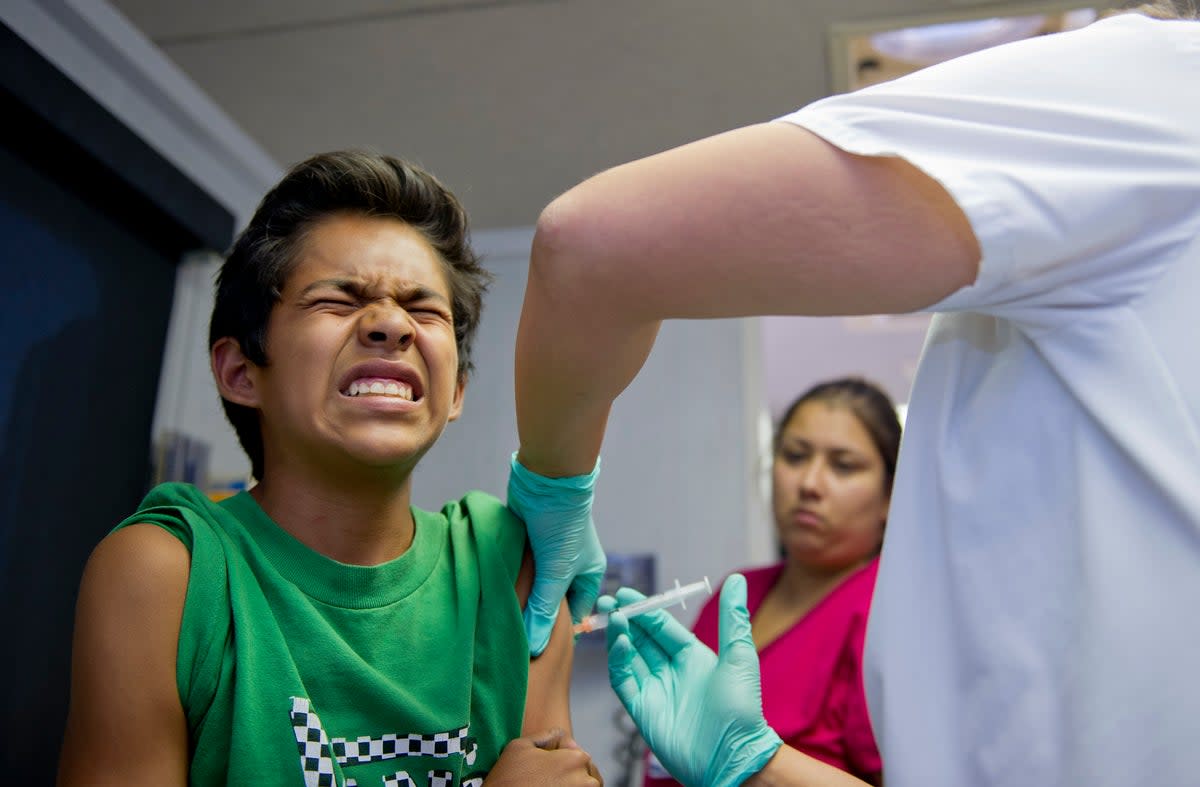 File Public school student Julio Valenzuela, 11, grimaces as he gets a vaccination at a free immunization clinic for students before the start of the school year (AFP via Getty Images)