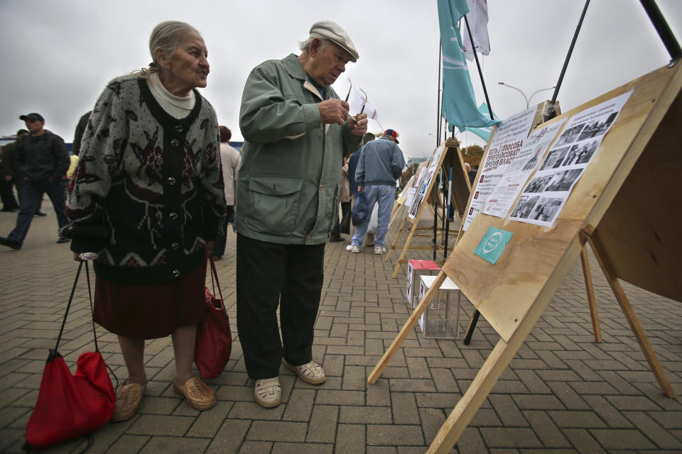 FILE - Belarusians read posters during an anti-election campaign picket in Minsk, Belarus, on Sept. 22, 2012. Belarusians will cast ballots Sunday in tightly controlled parliamentary and local elections that are set to cement an authoritarian leader's rule, despite calls for a boycott by an opposition leader who described the balloting as a "senseless farce." (AP Photo, File)