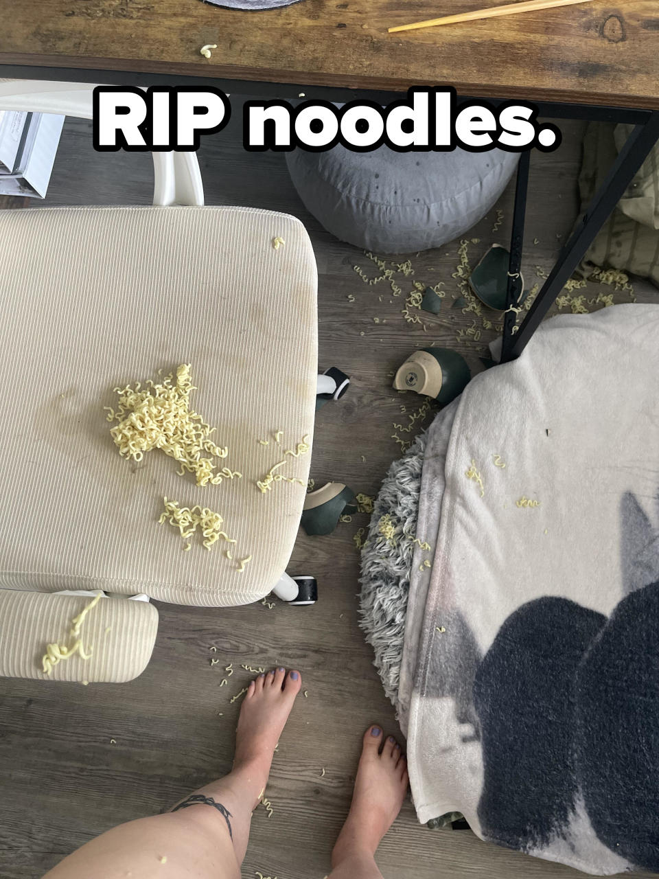 Person with spilled popcorn on a suitcase beside a cushion and chair, capturing a casual indoor moment