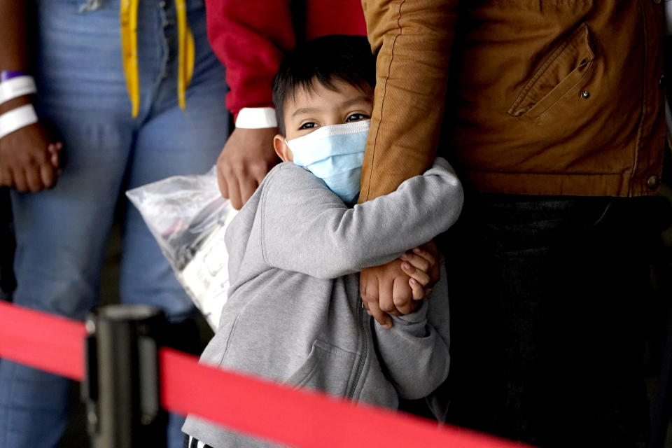 A migrant child holds onto a woman's arm as they wait to be processed by a humanitarian group after being released from U.S. Customs and Border Protection custody at a bus station, Wednesday, March 17, 2021, in Brownsville, Texas. Team Brownsville, a humanitarian group, is helping migrants seeking asylum with clothing and food as well as transportation to the migrant's final destination in the U.S. (AP Photo/Julio Cortez)