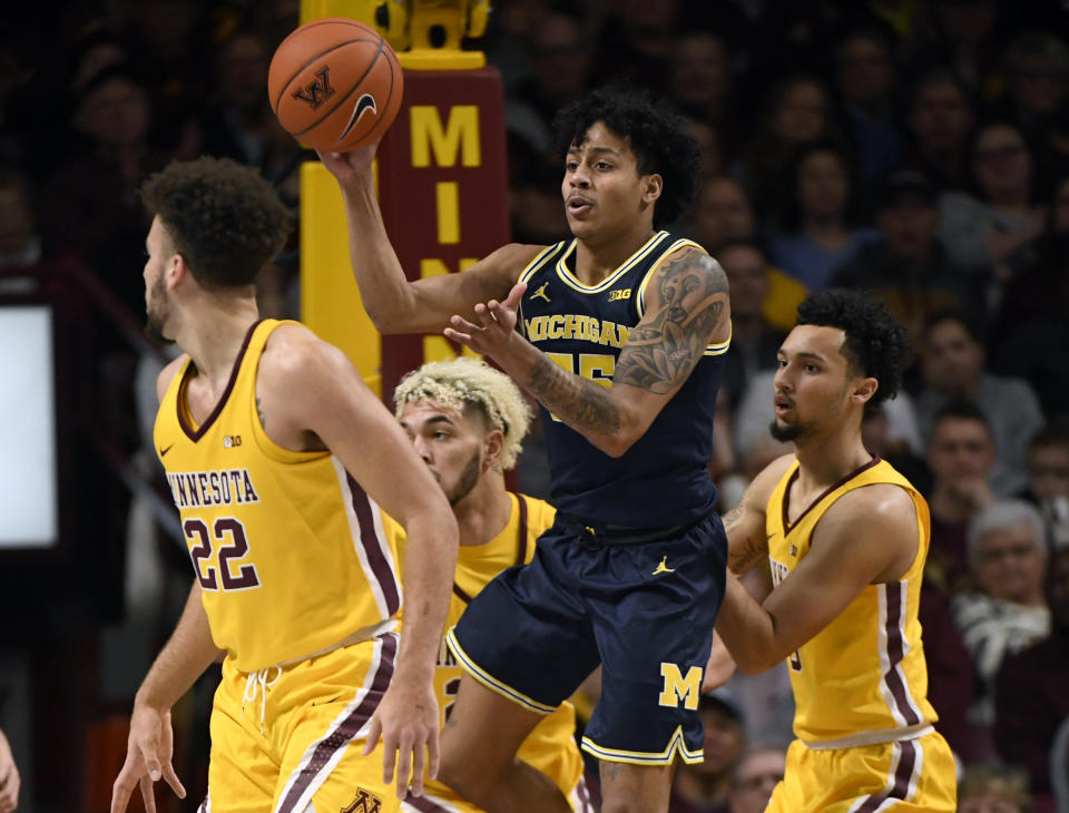 Michigan's Eli Brooks (55) passes the ball away from Minnesota's Gabe Kalscheur (22), Jarvis Omersa (21) and Payton Willis (0) in the first half during an NCAA college basketball game on Sunday, Jan. 12, 2020, in Minneapolis. (AP Photo/Hannah Foslien)