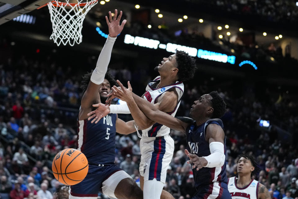 Florida Atlantic guard Nicholas Boyd (2) is fouled between Fairleigh Dickinson forward Ansley Almonor (5) and guard Joe Munden Jr. (1) in the second half of a second-round college basketball game in the men's NCAA Tournament in Columbus, Ohio, Sunday, March 19, 2023. (AP Photo/Michael Conroy)